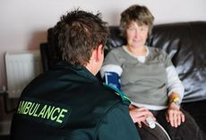 Paramedic  kneeling before female patient to assess